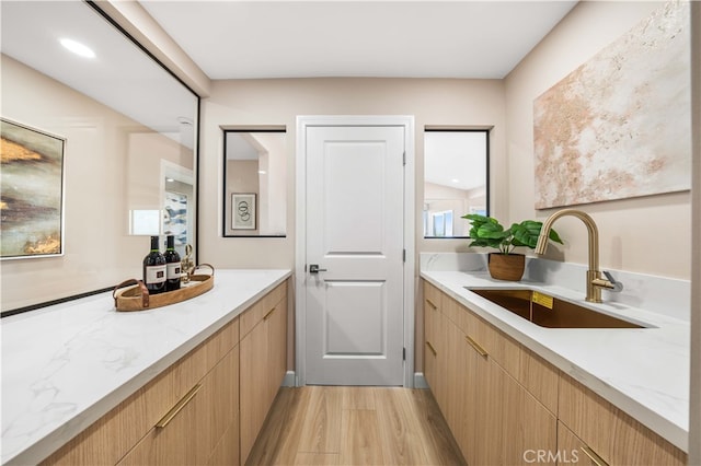 full bathroom with two vanities, wood finished floors, and a sink
