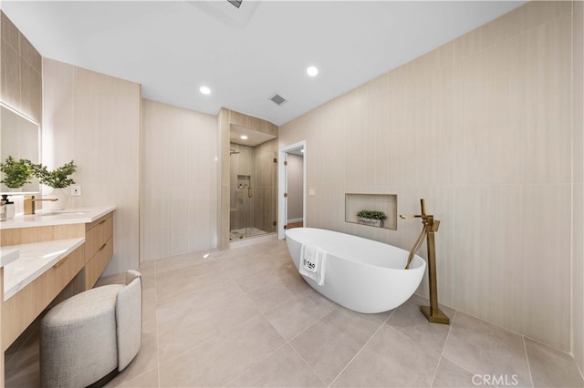 bathroom featuring tile patterned floors, visible vents, a freestanding tub, a shower stall, and vanity