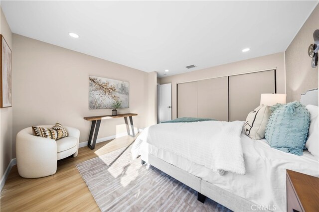 bedroom with light wood-style floors, a closet, baseboards, and visible vents