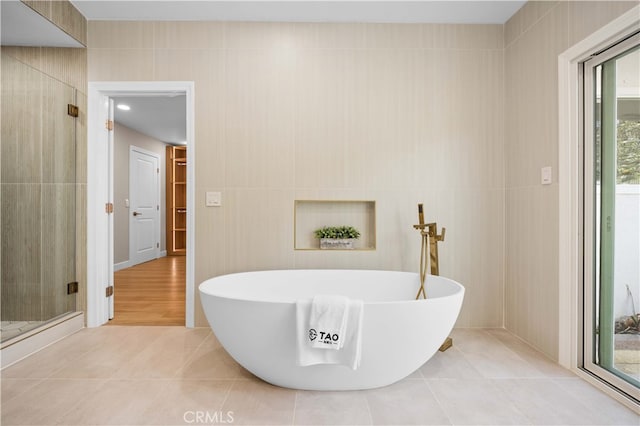 bathroom with a soaking tub, tile patterned flooring, and a stall shower
