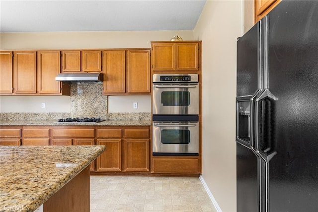 27674 Blue Topaz Dr, Menifee, CA 92585 - kitchen featuring brown cabinets, gas stovetop, double oven, under cabinet range hood, and black fridge