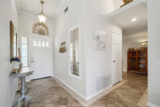 tiled entryway featuring baseboards, ornamental molding, and visible vents