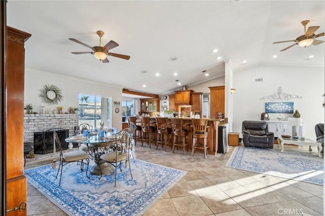 dining room with lofted ceiling, a ceiling fan, a brick fireplace, and crown molding
