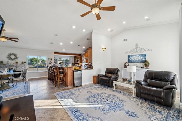 living room with vaulted ceiling, a ceiling fan, crown molding, light tile patterned flooring, and baseboards
