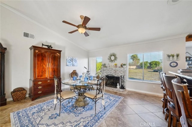dining space featuring vaulted ceiling, ceiling fan, a fireplace, ornamental molding, and visible vents