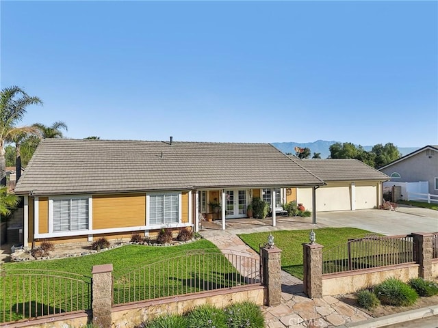 ranch-style home with french doors, concrete driveway, a front yard, and a fenced front yard