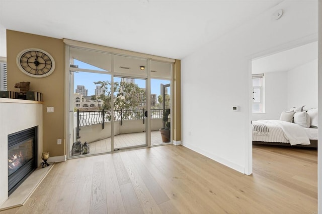 700 W Harbor Dr Unit 402, San Diego, CA 92101 - living room with light wood-type flooring, a glass covered fireplace, baseboards, and a wall of windows
