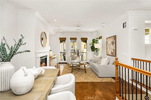 living room featuring recessed lighting, wood finished floors, visible vents, crown molding, and a glass covered fireplace