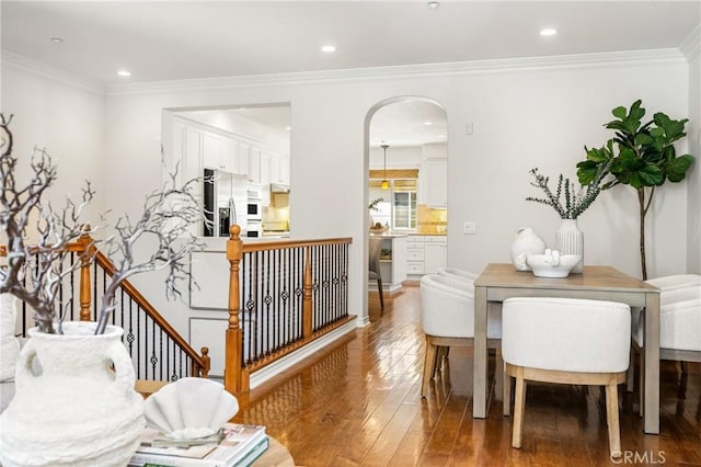 dining area with hardwood / wood-style flooring, arched walkways, ornamental molding, and recessed lighting