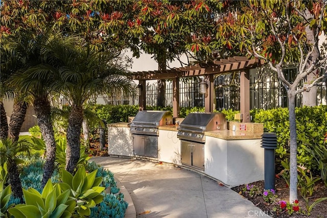view of patio / terrace featuring an outdoor kitchen, grilling area, fence, and a pergola