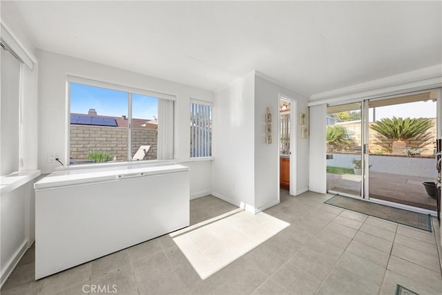 interior space featuring access to outside, light tile patterned floors, and multiple windows