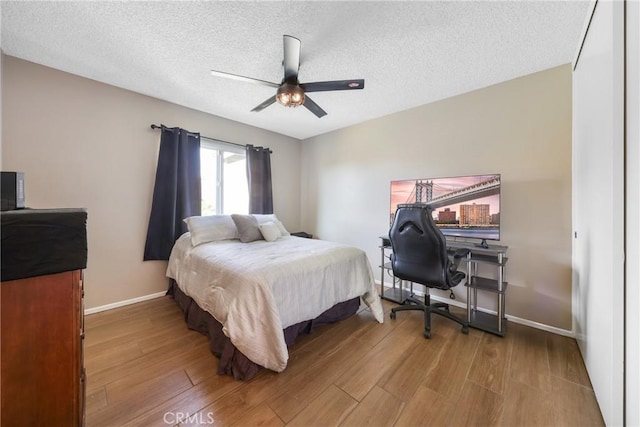 bedroom featuring baseboards, a textured ceiling, ceiling fan, and wood finished floors