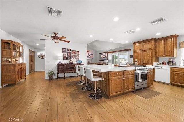 kitchen featuring light countertops, visible vents, brown cabinets, and dishwasher