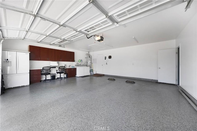 garage featuring baseboard heating, white fridge with ice dispenser, a garage door opener, secured water heater, and washer and clothes dryer