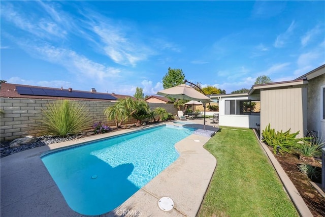 view of swimming pool with a yard, a pool with connected hot tub, a fenced backyard, and a patio area