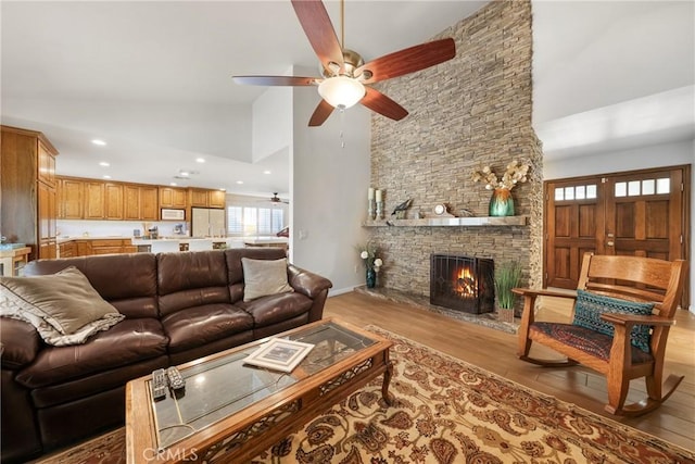 living area with ceiling fan, a fireplace, high vaulted ceiling, light wood finished floors, and recessed lighting