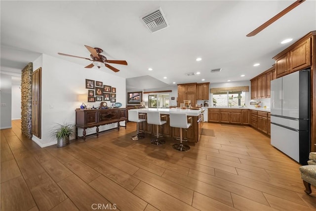 kitchen with a ceiling fan, visible vents, refrigerator, light countertops, and light wood-style flooring