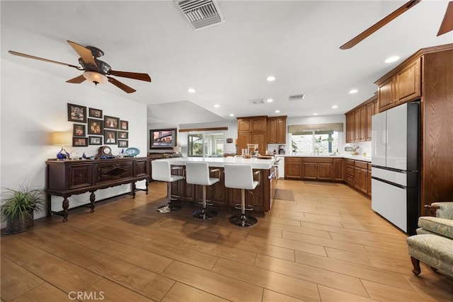 kitchen with light wood finished floors, light countertops, plenty of natural light, freestanding refrigerator, and visible vents