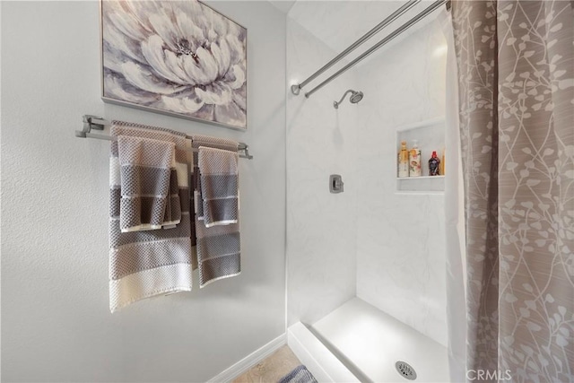bathroom featuring baseboards and a shower stall