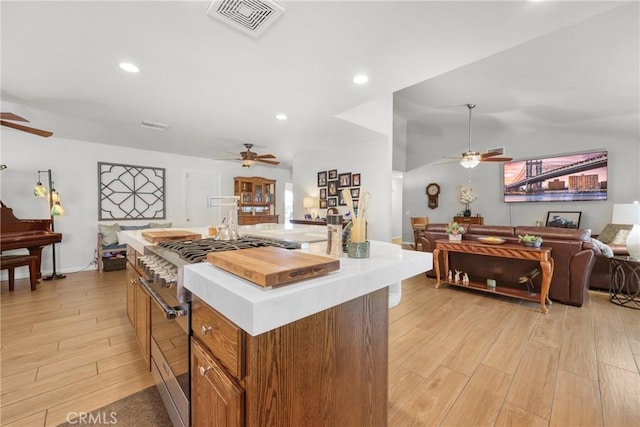kitchen with a ceiling fan, open floor plan, double oven range, light wood-type flooring, and visible vents