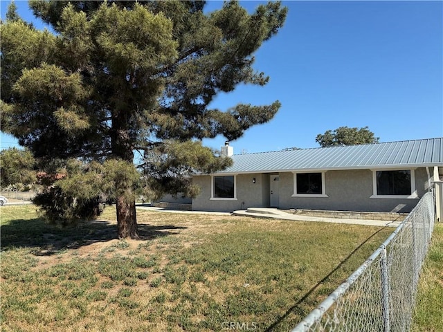 view of front facade with fence, metal roof, a front lawn, and stucco siding