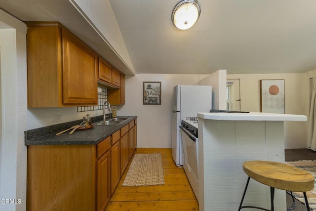 kitchen featuring a peninsula, light wood-style flooring, a sink, and brown cabinets