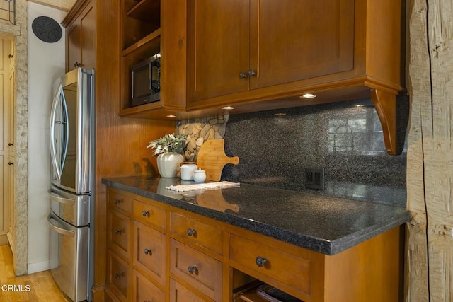 kitchen with brown cabinets, decorative backsplash, and freestanding refrigerator