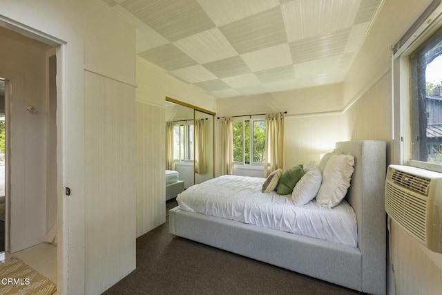 bedroom featuring a closet, an AC wall unit, and multiple windows