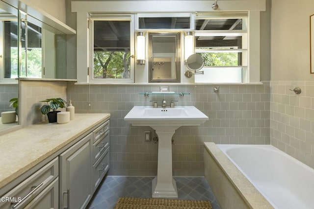 full bathroom featuring tile patterned flooring, plenty of natural light, a washtub, and tile walls