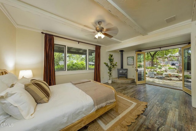 bedroom with beam ceiling, dark wood finished floors, access to exterior, multiple windows, and a wood stove