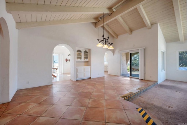 unfurnished dining area featuring arched walkways, beamed ceiling, light tile patterned floors, high vaulted ceiling, and plenty of natural light