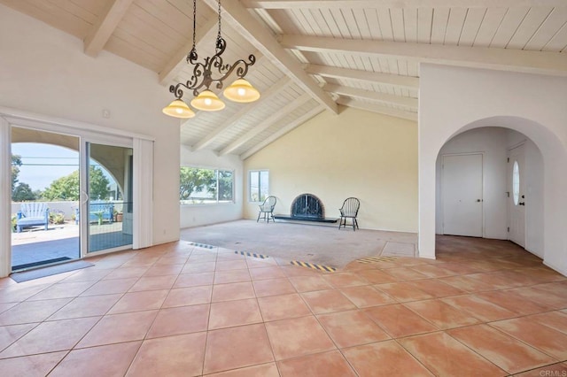 unfurnished living room with light tile patterned flooring, a chandelier, beam ceiling, light colored carpet, and wooden ceiling