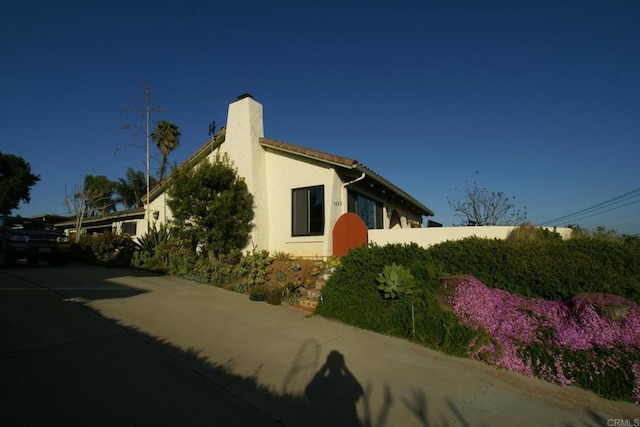 view of side of home with a chimney and stucco siding
