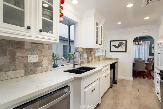 kitchen featuring light wood finished floors, stainless steel dishwasher, a sink, visible vents, and white cabinetry