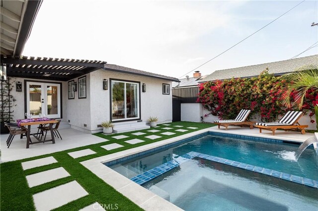 back of house featuring a pergola, a lawn, a patio, stucco siding, and a pool with connected hot tub