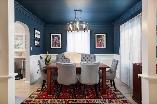 dining space with a decorative wall, arched walkways, a notable chandelier, and a healthy amount of sunlight