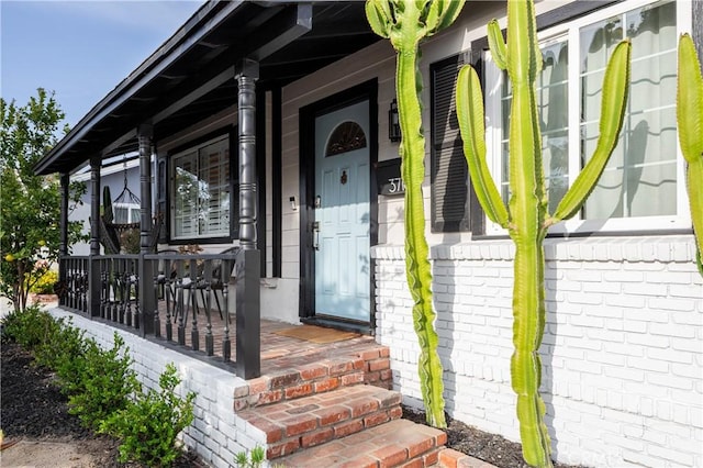 property entrance featuring brick siding and covered porch