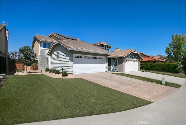view of front of home with a garage, driveway, a tiled roof, roof mounted solar panels, and a front yard