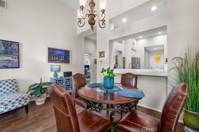 dining area featuring visible vents, a towering ceiling, wood finished floors, baseboards, and a chandelier