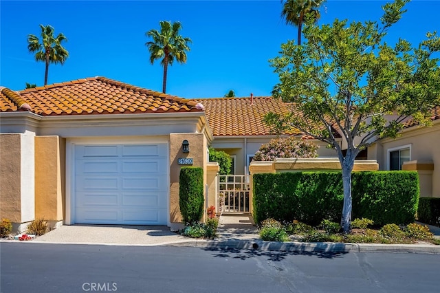 view of front facade with a tiled roof, driveway, a garage, fence, and stucco siding