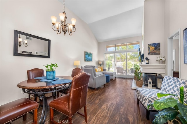 dining area featuring visible vents, dark wood finished floors, high vaulted ceiling, a glass covered fireplace, and an inviting chandelier