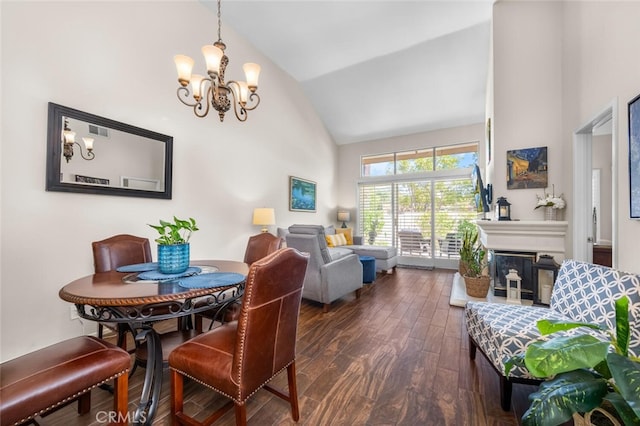 dining space with visible vents, high vaulted ceiling, a notable chandelier, a glass covered fireplace, and dark wood-type flooring