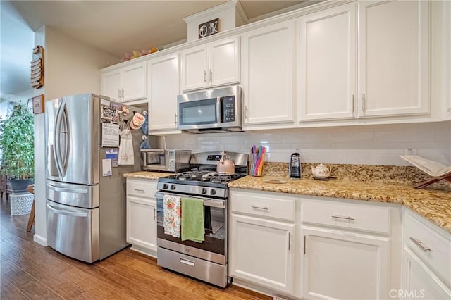 718 Marybelle Dr, Merced, CA 95348 - kitchen with white cabinets, decorative backsplash, stainless steel appliances, and light wood finished floors