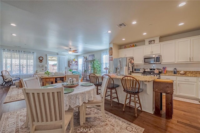 718 Marybelle Dr, Merced, CA 95348 - kitchen featuring white cabinets, stainless steel appliances, visible vents, wood finished floors, and a breakfast bar