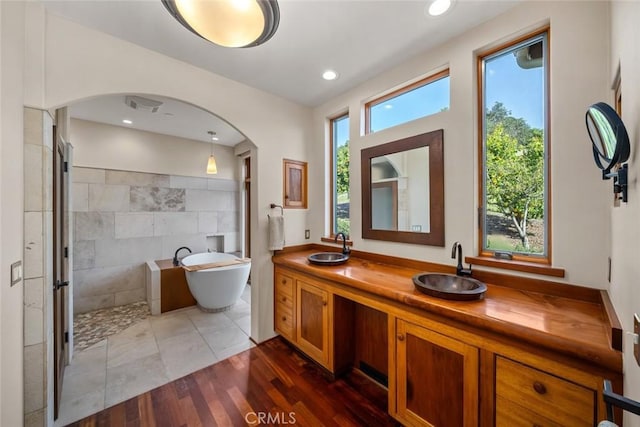 full bath with a freestanding tub, a sink, visible vents, and double vanity