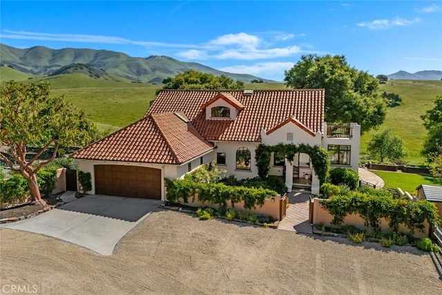 mediterranean / spanish house with an attached garage, concrete driveway, stucco siding, and a mountain view