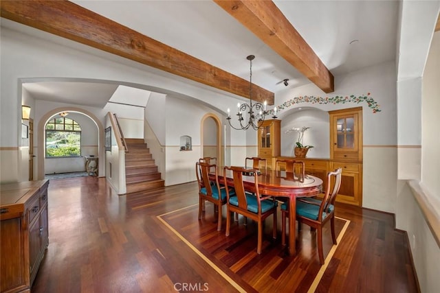 dining area with arched walkways, dark wood-type flooring, beamed ceiling, stairs, and a notable chandelier