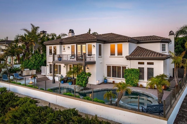7076 Heron Cir, Carlsbad, CA 92011 - back of property at dusk with an in-ground hot tub, a balcony, a chimney, an outdoor pool, and a patio