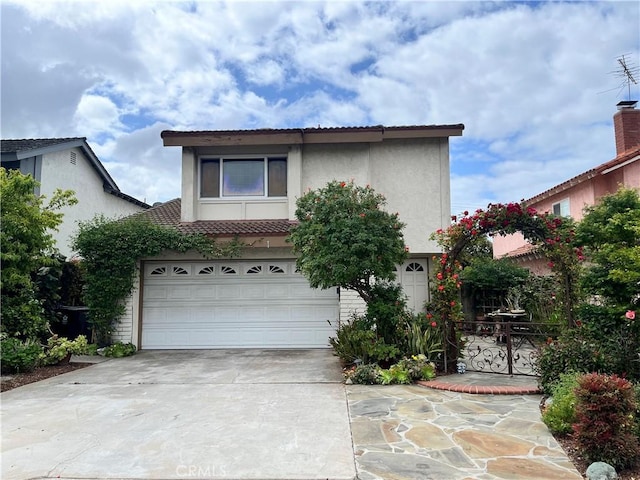 view of front facade with stucco siding, a tiled roof, concrete driveway, and an attached garage