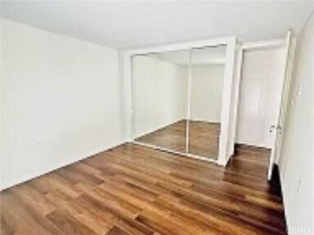 unfurnished bedroom with wood finished floors and a closet